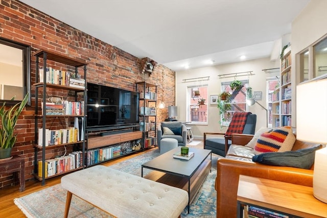 living room with a healthy amount of sunlight, brick wall, and wood finished floors