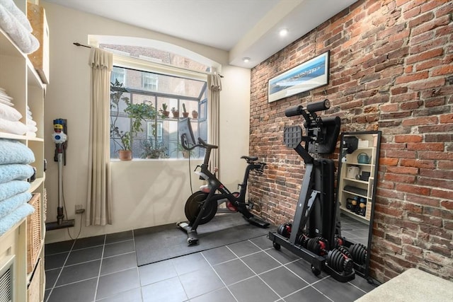 workout room with brick wall and dark tile patterned flooring