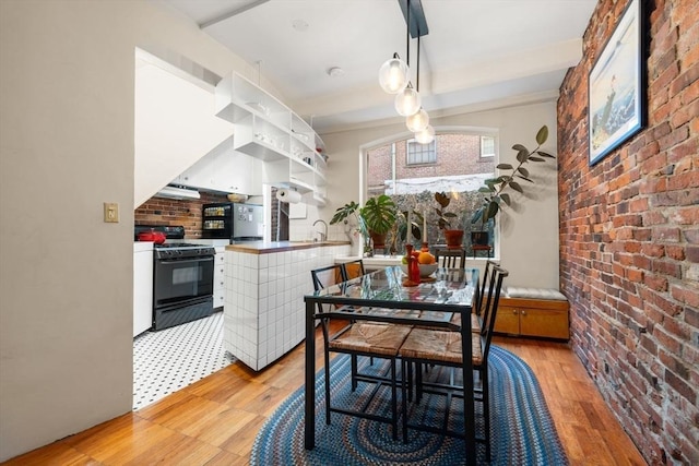 dining room with brick wall and light wood-style floors