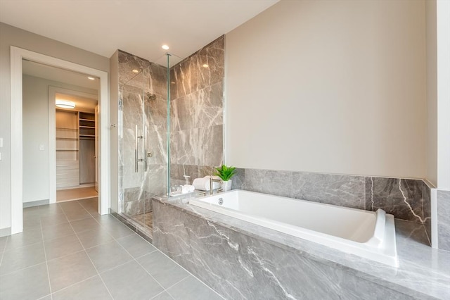 full bath featuring a bath, tile patterned floors, a spacious closet, a marble finish shower, and recessed lighting