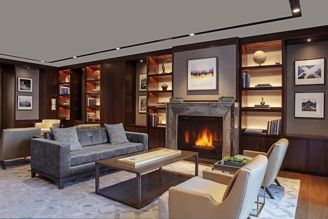 sitting room with a high end fireplace, built in features, and light wood-type flooring