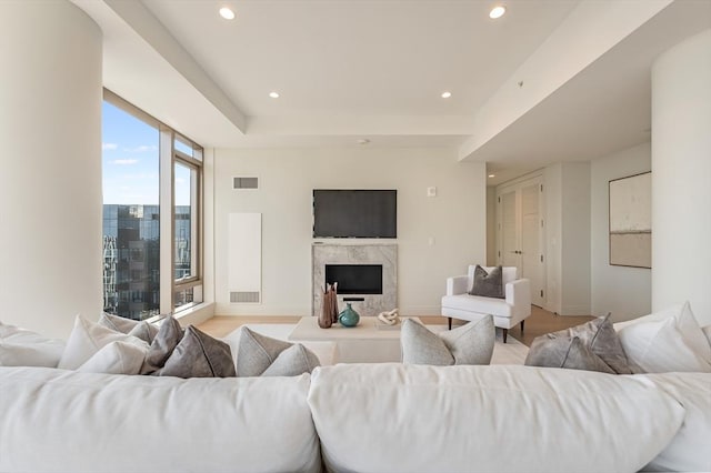 living area with visible vents, recessed lighting, a tray ceiling, and a fireplace