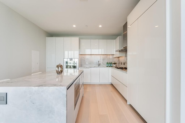 kitchen featuring light stone countertops, a center island, recessed lighting, decorative backsplash, and modern cabinets