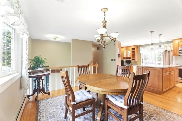 dining area featuring light wood finished floors, a notable chandelier, and baseboard heating