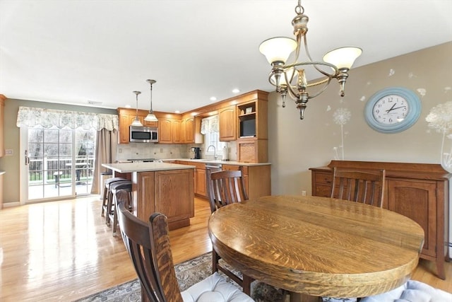 dining area featuring light wood finished floors, recessed lighting, and an inviting chandelier
