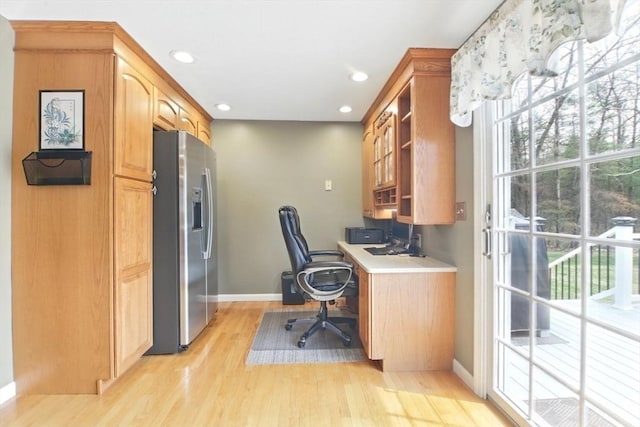 office space featuring built in desk, light wood finished floors, baseboards, and a healthy amount of sunlight