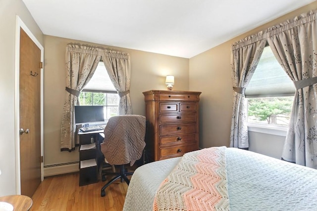 bedroom with a baseboard radiator and wood finished floors