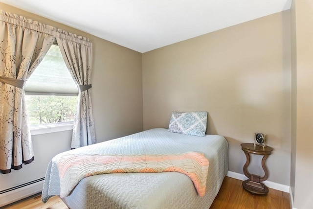 bedroom featuring baseboard heating, wood finished floors, and baseboards