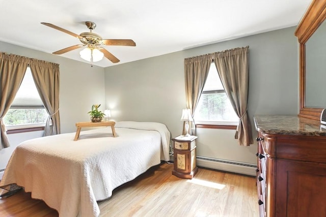 bedroom featuring a baseboard radiator, light wood-type flooring, a ceiling fan, and multiple windows