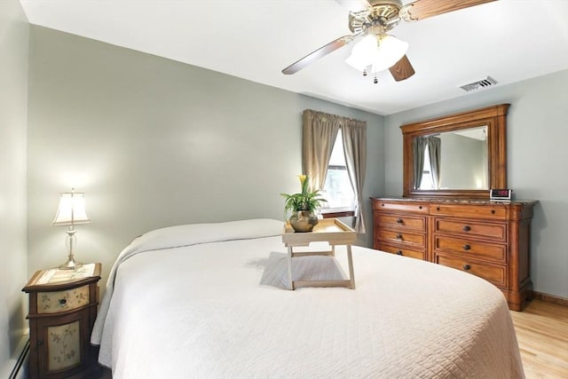 bedroom featuring visible vents, ceiling fan, baseboard heating, baseboards, and light wood finished floors
