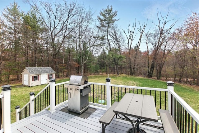 wooden deck with an outbuilding, a lawn, area for grilling, and a wooded view