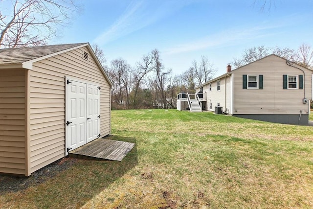 view of yard with an outdoor structure, central air condition unit, and a storage shed