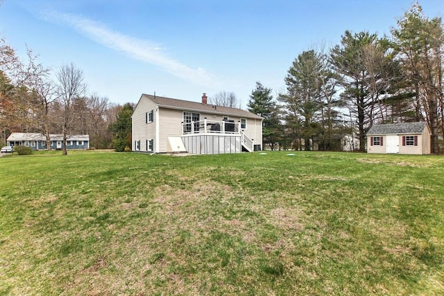 back of property with an outbuilding, a lawn, a wooden deck, and a chimney