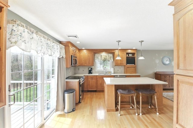kitchen featuring visible vents, light wood-type flooring, a center island, and appliances with stainless steel finishes