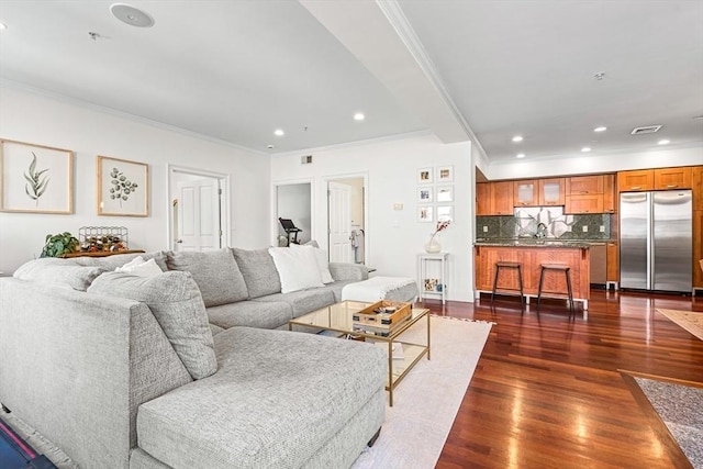 living room featuring sink, dark wood-type flooring, and ornamental molding