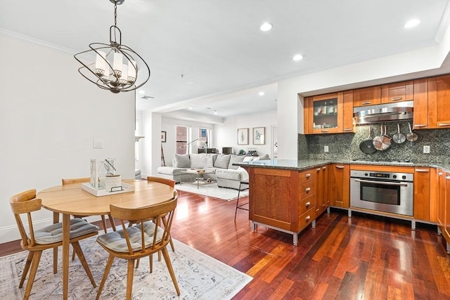 kitchen featuring pendant lighting, dark hardwood / wood-style floors, kitchen peninsula, decorative backsplash, and oven