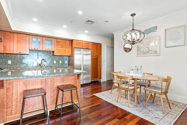 kitchen featuring light stone counters, ornamental molding, dark hardwood / wood-style floors, and built in fridge