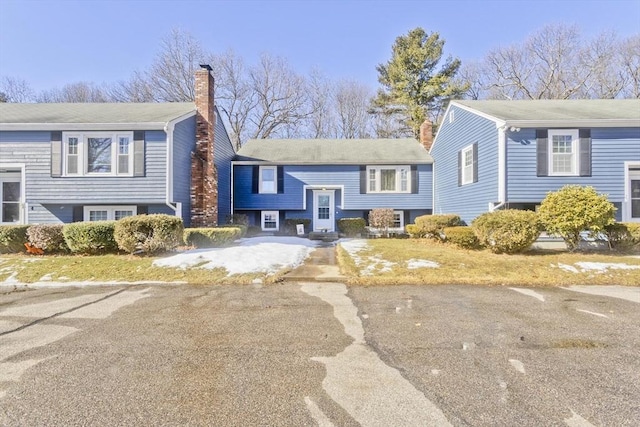 bi-level home with aphalt driveway and a chimney