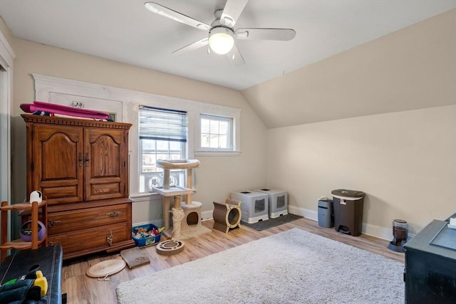 interior space with a ceiling fan, vaulted ceiling, wood finished floors, and baseboards