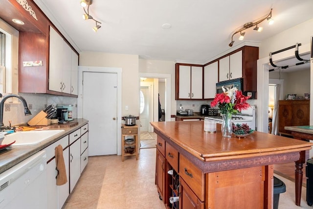 kitchen featuring a sink, tasteful backsplash, a center island, white appliances, and light floors