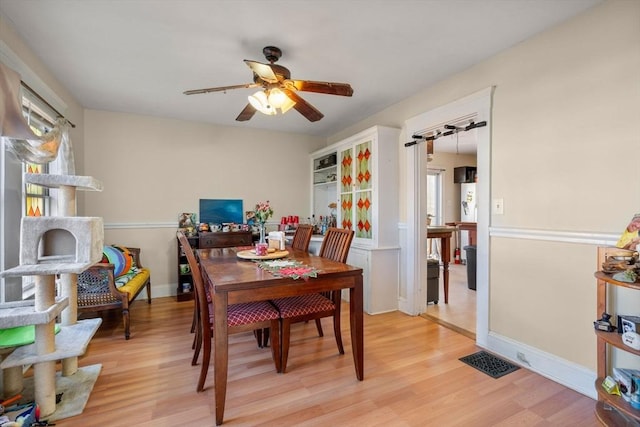 dining room featuring light wood-type flooring, baseboards, visible vents, and ceiling fan