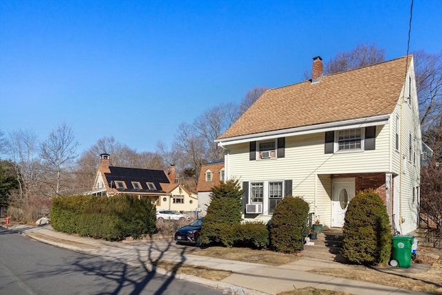 view of front of property featuring cooling unit, a chimney, and roof with shingles