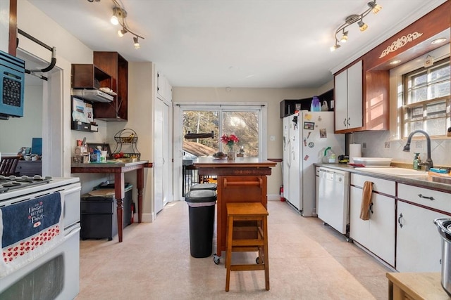 kitchen with track lighting, light floors, white appliances, and a sink