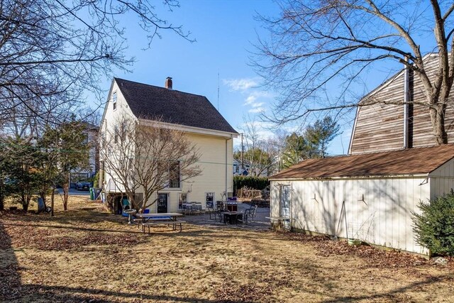 view of property exterior featuring a patio, an outdoor structure, and a chimney