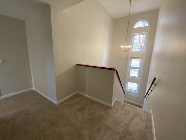 staircase featuring carpet flooring, baseboards, and a chandelier