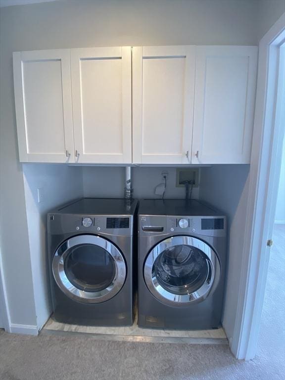 laundry room featuring washing machine and dryer, cabinet space, and baseboards