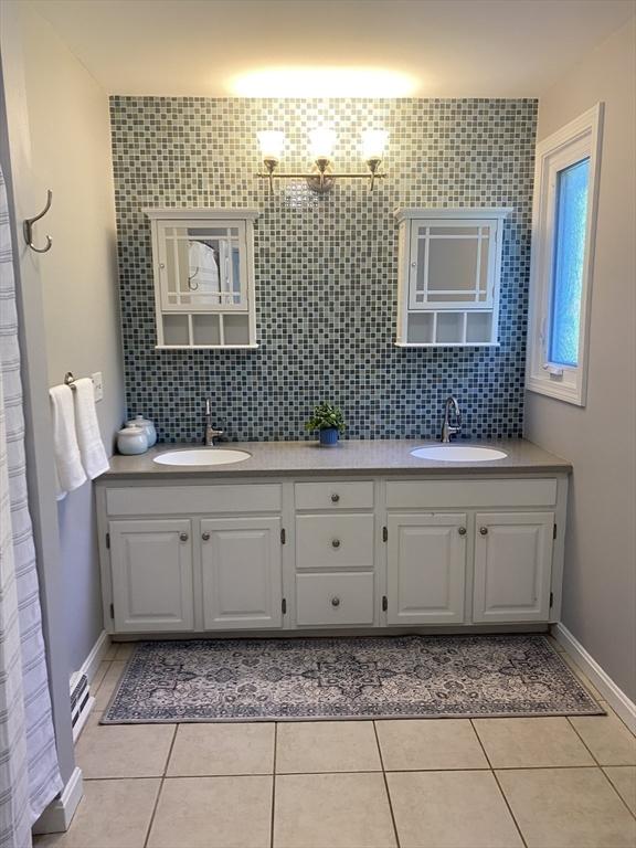 full bathroom with double vanity, tile patterned floors, backsplash, and baseboards