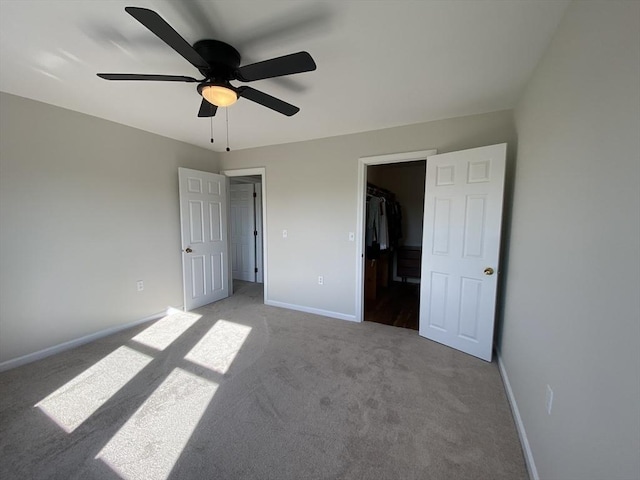 unfurnished bedroom featuring carpet floors, baseboards, a spacious closet, ceiling fan, and a closet