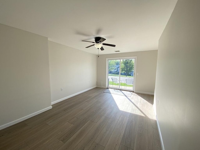 spare room with dark wood-style flooring, a ceiling fan, and baseboards