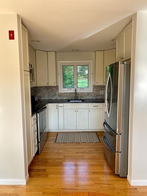 kitchen featuring appliances with stainless steel finishes, a sink, dark countertops, and decorative backsplash