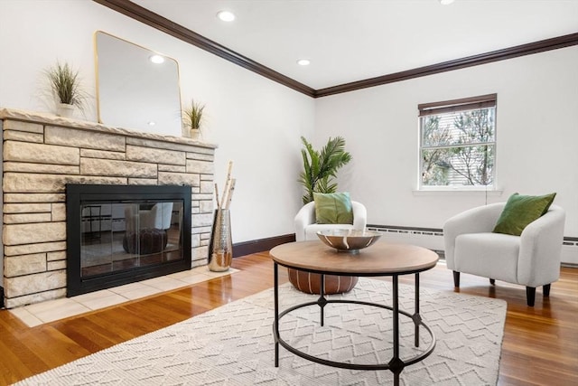 living area featuring ornamental molding, a baseboard radiator, wood finished floors, a fireplace, and baseboards