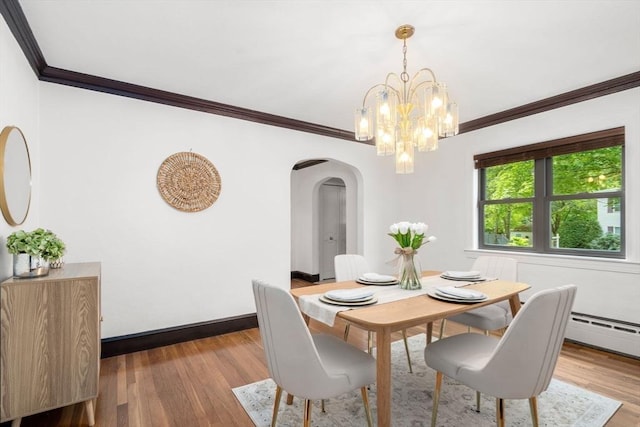 dining space featuring arched walkways, ornamental molding, wood finished floors, a chandelier, and baseboards