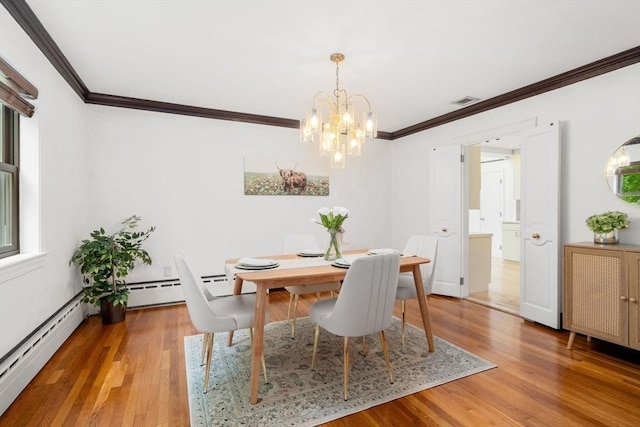 dining area with a chandelier, crown molding, wood finished floors, and baseboard heating