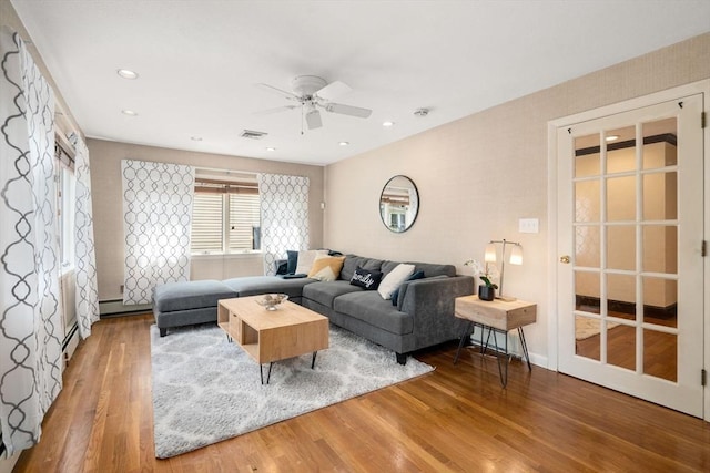 living area with a ceiling fan, wood finished floors, baseboard heating, and recessed lighting