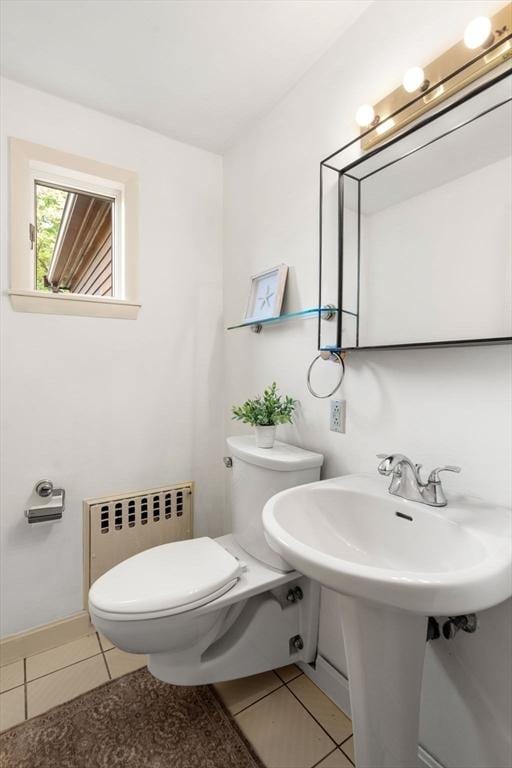 half bath featuring radiator, tile patterned flooring, and toilet