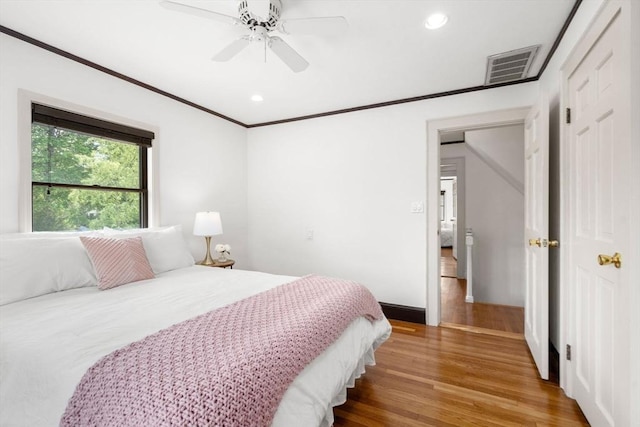 bedroom with wood finished floors, recessed lighting, ornamental molding, a ceiling fan, and baseboards