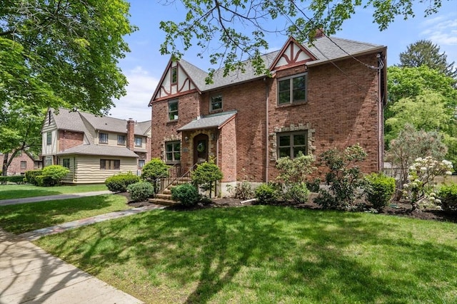 tudor house featuring brick siding and a front yard