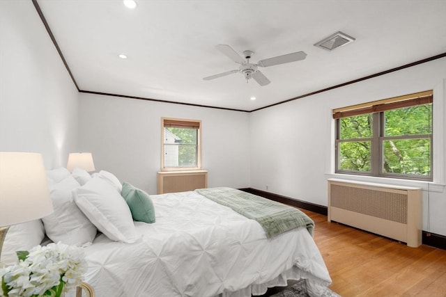 bedroom featuring radiator, crown molding, light wood-style floors, baseboards, and ceiling fan