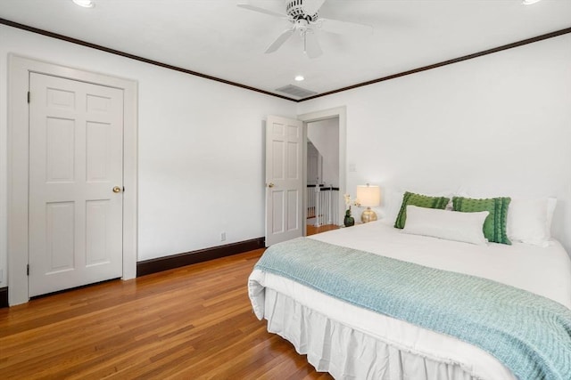 bedroom featuring recessed lighting, crown molding, wood finished floors, baseboards, and a ceiling fan