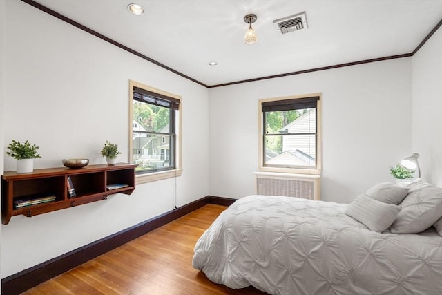 bedroom featuring crown molding, multiple windows, wood finished floors, baseboards, and recessed lighting