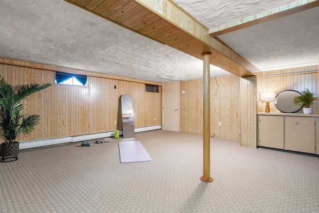 finished basement with carpet flooring, a textured ceiling, wooden walls, and a baseboard heating unit