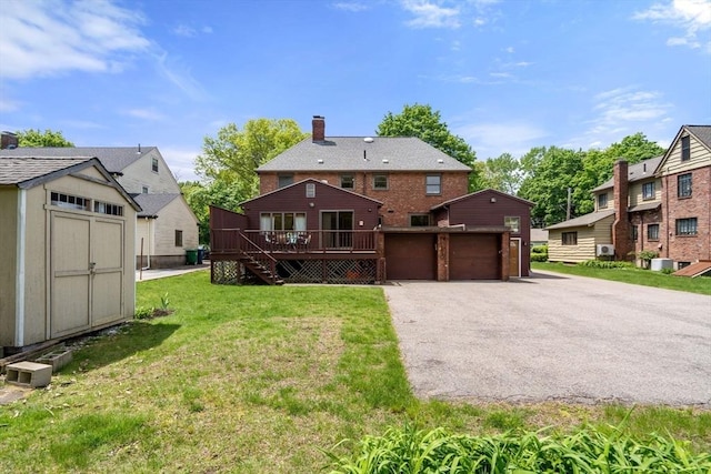 back of property with an outdoor structure, a deck, a lawn, and a shed