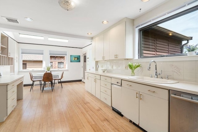 kitchen featuring dishwasher, a sink, light countertops, backsplash, and recessed lighting