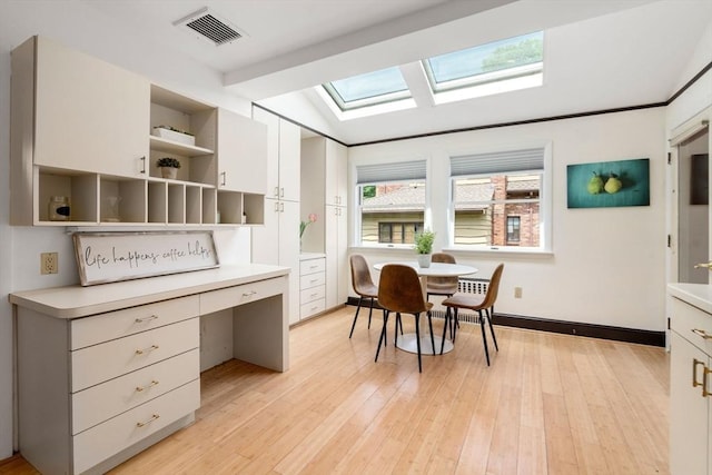 dining area featuring a skylight, light wood-style flooring, and baseboards