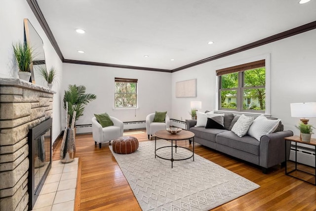 living area featuring a baseboard heating unit, crown molding, plenty of natural light, a fireplace, and recessed lighting