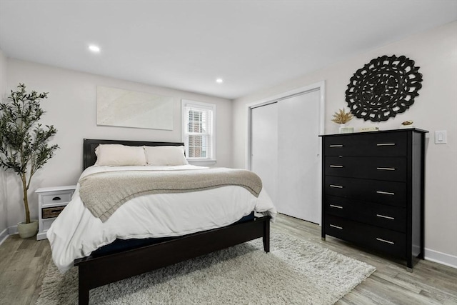 bedroom with a closet, baseboards, recessed lighting, and light wood-style floors